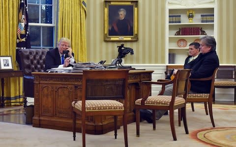 Donald Trump speaking on the phone with Australia's Prime Minister Malcolm Turnbull, alongside former Chief Strategist Steve Bannon, right, and former National Security Advisor Michael Flynn, from the Oval Office of the White House on January 28, 2017 - Credit: MANDEL NGAN/AFP/Getty Images