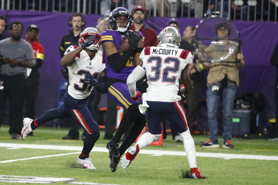 Minnesota Vikings wide receiver Justin Jefferson, center, catches a pass between New England Patriots cornerback Jonathan Jones, left, and safety Devin McCourty (32) during the second half of an NFL football game, Thursday, Nov. 24, 2022, in Minneapolis. (AP Photo/Bruce Kluckhohn)