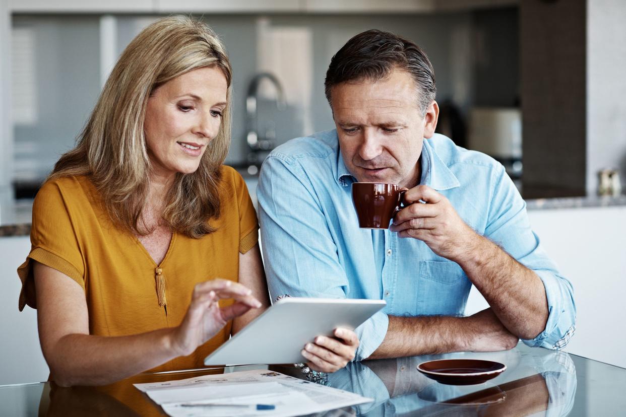 couple at kitchen table looking over tablet and finances