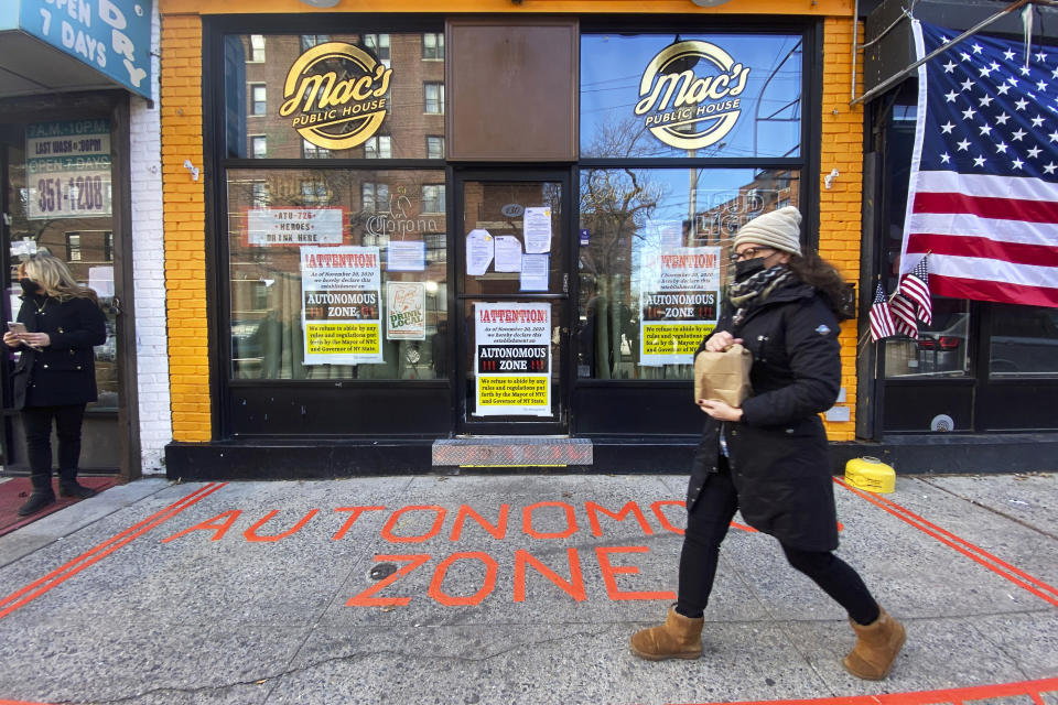 A woman walks by Mac's Public House before a press conference in Staten Island on Monday, Dec 7, 2020, in New York. (AP Photo/Eduardo Munoz Alvarez)