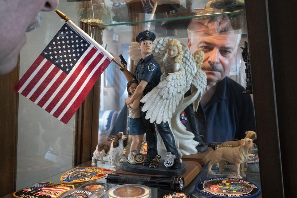 Retired NYPD Officer Mark DeMarco, is seen in a reflection off a display cabinet where he keeps memorabilia from 9/11 including the small flashlight which he used to help him navigate his way out of the rubble of the fallen skyscrapers, in his home in the Staten Island borough of New York on Tuesday, Aug. 3, 2021. He worries that the public memory of the attacks is fading, that the passage of time has created a false sense of security. "Have fun with life. Don't be afraid," he says. "But be mindful." (AP Photo/Wong Maye-E)