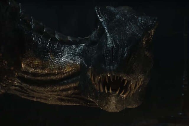 An Indoraptor with sharp teeth looks at the camera in the  Jurassic Park film series.