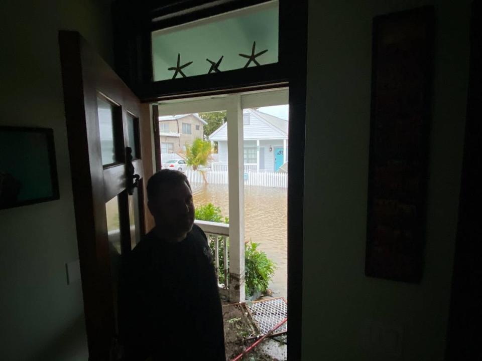 Aaron Pearlman stands in the doorway of his Catherine Street home in the Bahama Village neighborhood of Key West on Wednesday, Sept. 28, 2022, as seawater flows down the road.