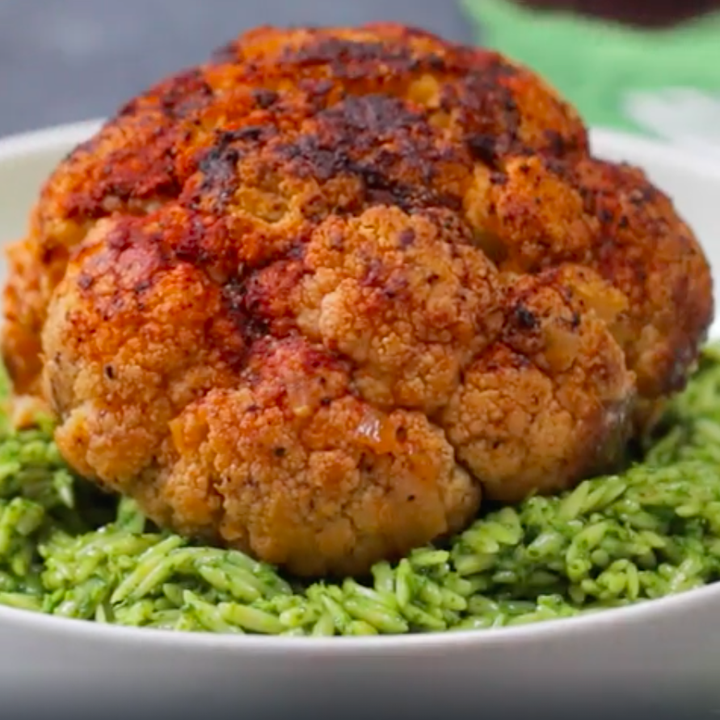 a whole braised cauliflower over salsa verde orzo