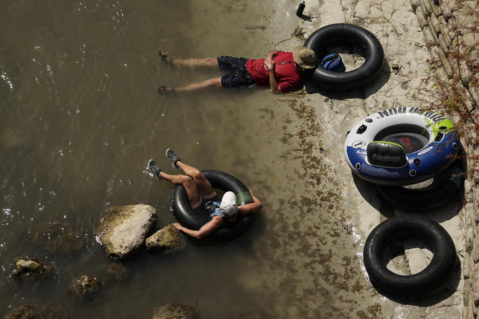 FILE - A couple take a break on the banks of the Comal River, July 26, 2023, in New Braunfels, Texas, as the area continues to feel the effects of triple-digit temperatures. Across the U.S., many people are living through one of the most brutal summers of their lives and reckoning with the idea that climate change is only going to make matters worse in the coming decades. (AP Photo/Eric Gay, File)