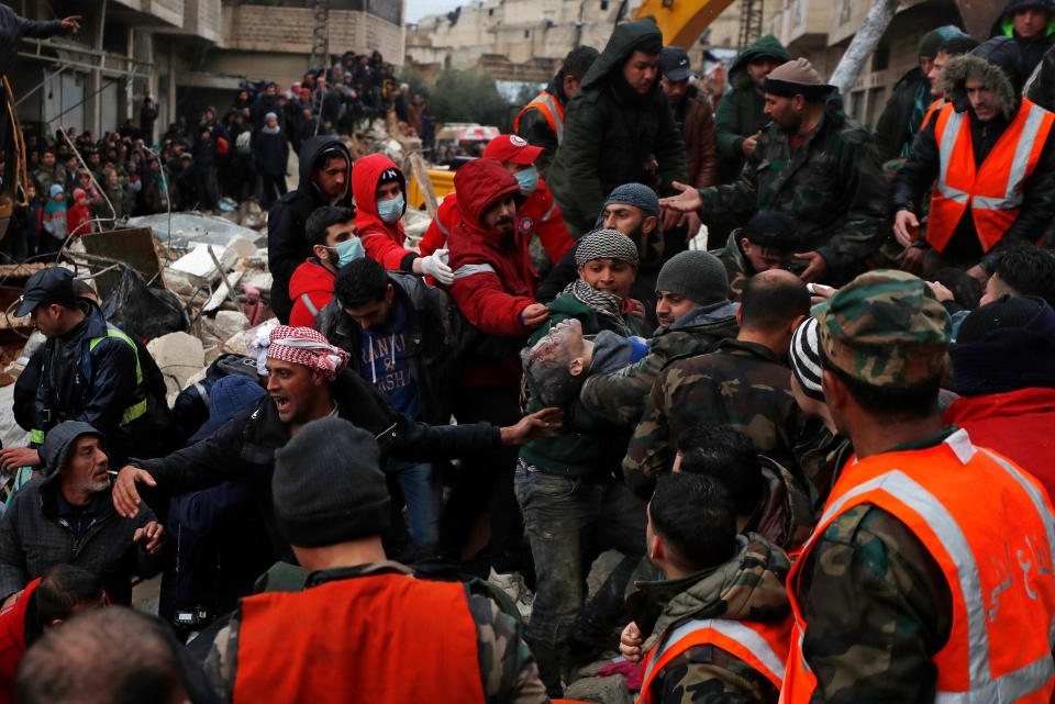 Civil defense workers and security forces carry an earthquake victim as they search through the wreckage of collapsed buildings in Hama, Syria.<span class="copyright">Omar Sanadik—AP</span>