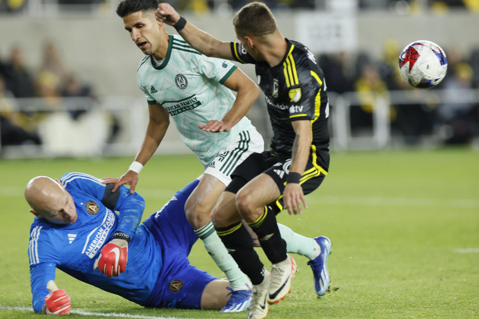 Atlanta United's Brad Guzan, left, makes a save as teammate Luis Abram, center, and Columbus Crew's Alexandru Matan, right, fight for position during the second half of an MLS playoff soccer match Sunday, Nov. 12, 2023, in Columbus, Ohio. (AP Photo/Jay LaPrete)