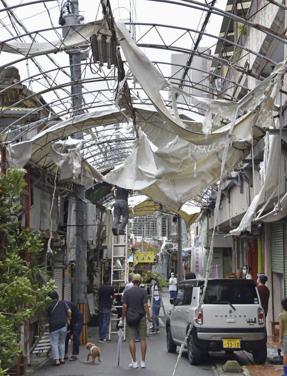 Workers try to restore the destruction caused by Typhoon Khanun, at a shopping district in Naha, Okinawa prefecture, southern Japan Thursday, Aug. 3, 2023. The typhoon that damaged homes and knocked out power on Okinawa and other Japanese islands this week was slowly moving west Thursday but is forecast to make a U-turn and dump even more rain on the archipelago. (Kyodo News via AP)
