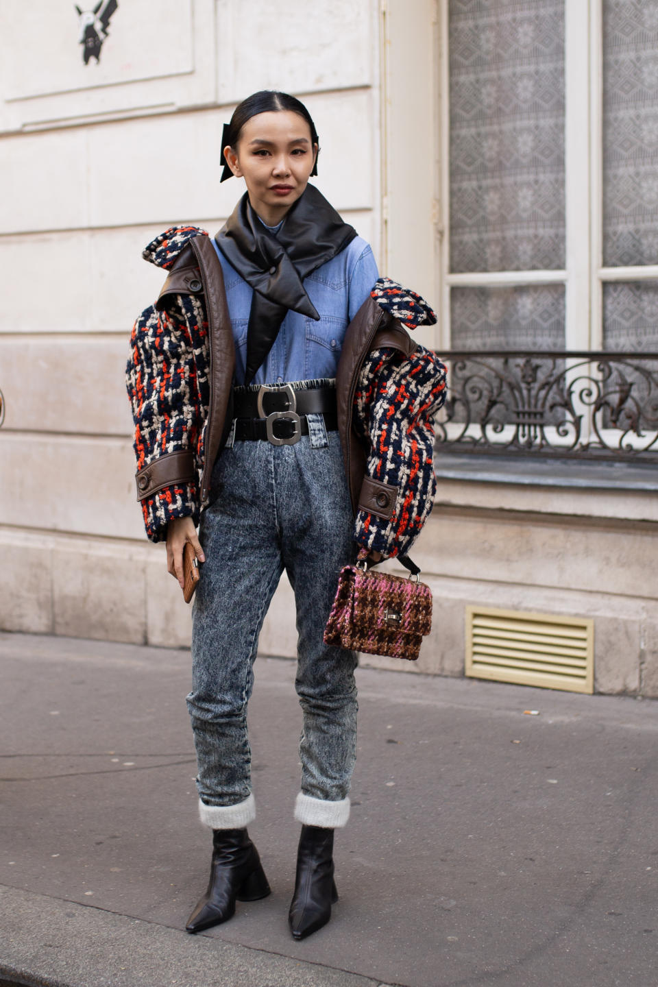 A woman wearing jeans, a blue top, red and black puffer coat, and two belts.