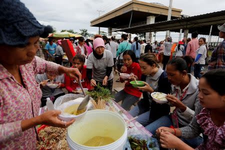 Workers eat breakfast at a market outside Complete Honour Footwear Industrial, a footwear factory owned by a Taiwan company, before their shift at the factory, in Kampong Speu, Cambodia, July 5, 2018. REUTERS/Ann Wang