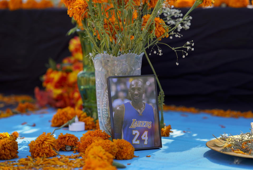 Flores de cempasúchil yacen junto a una imagen del fallecido basquetbolista de los Lakers de Los Ángeles, Kobe Bryant, en una ofrenda colocada por el Día de los Muertos, en Los Ángeles, el jueves 29 de octubre de 2020. (AP Foto/Damian Dovarganes)