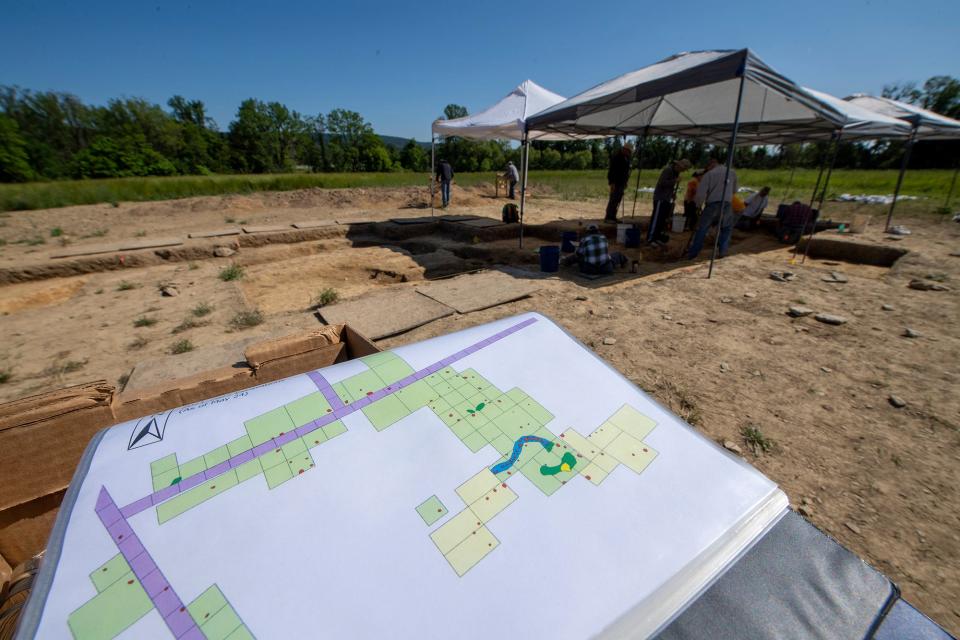 A map of the dig site sits in northernly orientation to match the orientation of the current stockade dig. The area in blue matches up with the stockade trench in the background at the Camp Security dig site on Thursday May 25, 2023.