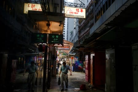 A man walks between stalls in an alley in the Central business district in Hong Kong