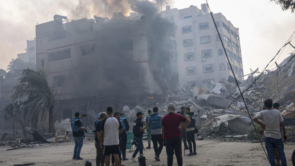 Journalists observe Palestinians inspecting the rubble of a building after it was struck by an Israeli airstrike in Gaza City on Oct. 8, 2023. (Fatima Shbair/AP)