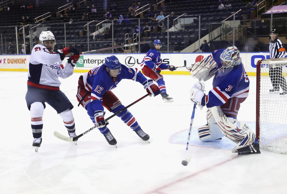 Igor Shesterkin, right, of the New York Rangers, shoots the puck away from Garnet Hathaway, left, of the Washington Capitals during the second period of an NHL hockey game Monday, May 3, 2021, in New York. (Bruce Bennett/Pool Photo via AP)