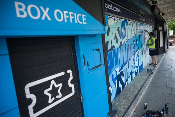 Street artist Captain Kris works on a mural on the temporary hoardings outside the O2 Forum in Kentish Town: Getty