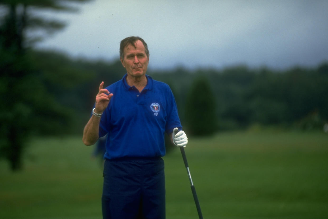 Then-President George H.W. Bush speaks to the press while golfing (Cynthia Johnson / Getty Images file)