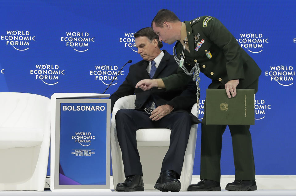 Jair Bolsonaro, President of Brazil, left, takes his seat for a session at the annual meeting of the World Economic Forum in Davos, Switzerland, Tuesday, Jan. 22, 2019. (AP Photo/Markus Schreiber)