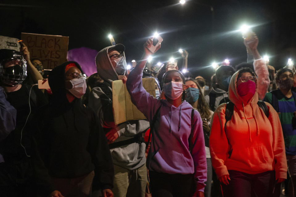 Protesters march from Kenton Park to the Portland Police Association in Portland, Ore., Thursday, Aug. 20, 2020. Portland police say people in a group of about 100 late Thursday and early Friday sprayed the building with graffiti, hurled rocks and bottles at agents and shined laser lights at them. (Mark Graves /The Oregonian via AP)
