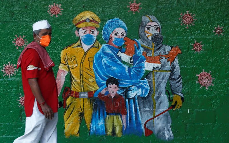 A man wearing a protective mask walks past a mural of frontline workers amidst the spread of the coronavirus disease (COVID-19), in Mumbai