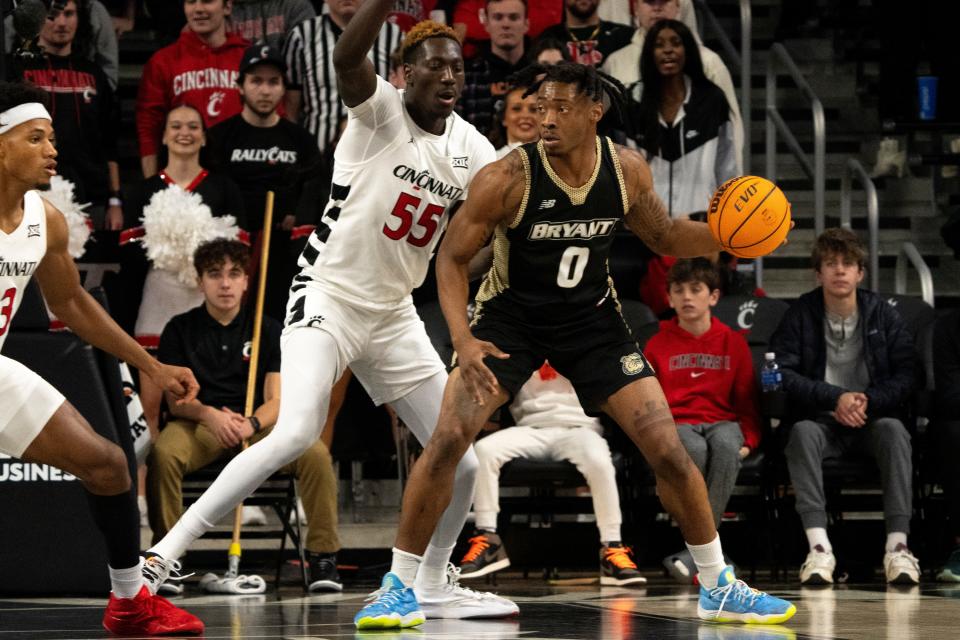 Bryant Bulldogs guard Earl Timberlake (0) handles the ball as Cincinnati Bearcats forward Aziz Bandaogo (55) guards him in the first half of the NCAA Basketball game between the Bryant Bulldogs and Cincinnati Bearcats at Fifth Third Arena in Cincinnati on Tuesday, Dec. 12, 2023.