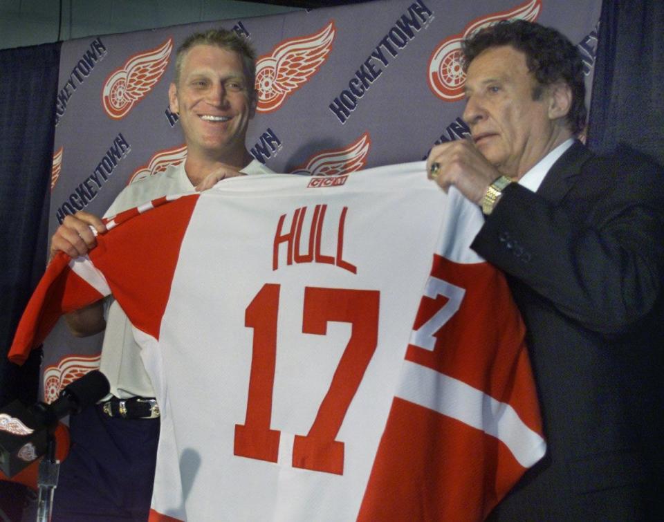 Newest Detroit Red Wing BRETT HULL is handed his new jersey by Wings' owner MIKE ILITCH during the formal press conference when he was introduced in 2001.