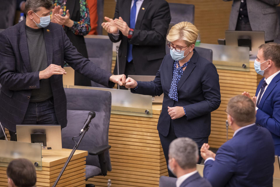 Members of Lithuania's parliament applaud Lithuania's Homeland Union and Lithuanian Christian Democrats party leader Ingrida Simonyte, center, at the parliament in Vilnius, Lithuania, Tuesday, Nov. 24, 2020. Lithuania's parliament approved Ingrida Simonyte as the new prime minister on Tuesday. (AP Photo/Mindaugas Kulbis)