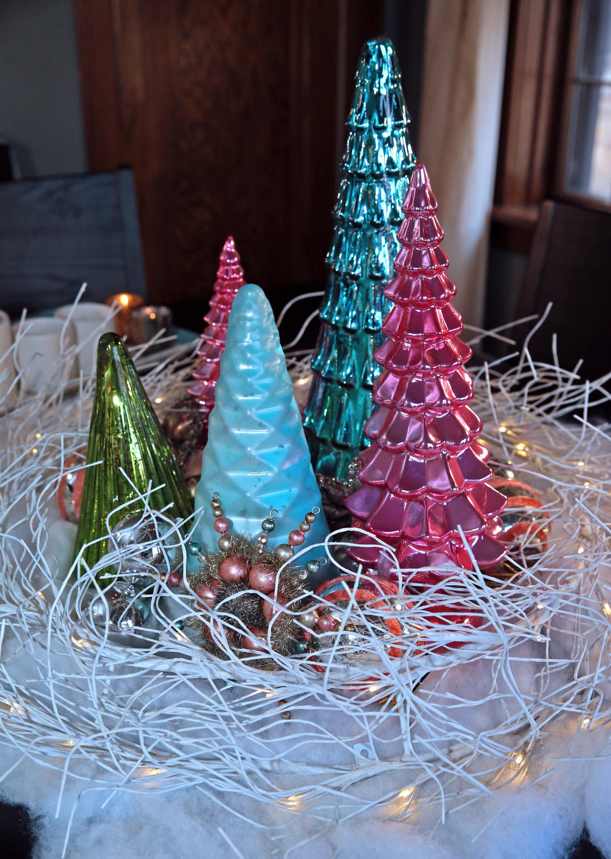 Brightly colored Christmas trees and ornaments sit in the middle of a white wire wreath on the dining room table at Mitchell Conklin's home.