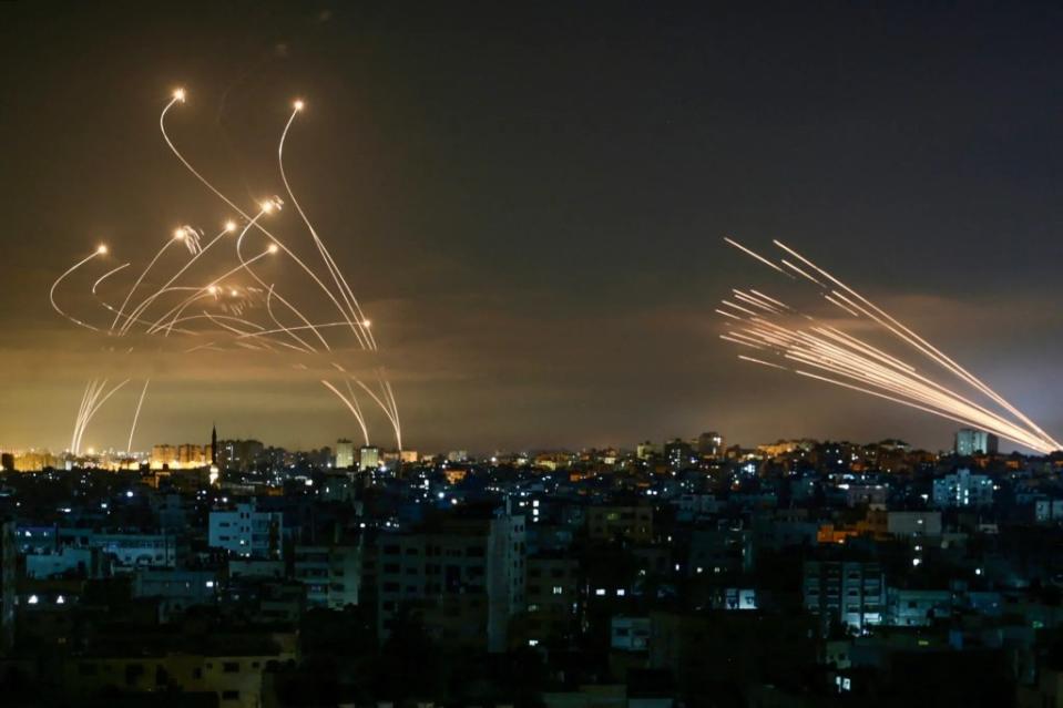 The Israeli Iron Dome missile defense system (L) intercepts rockets (R) fired by Hamas toward southern Israel from Beit Lahia in the northern Gaza Strip on May 14, 2021. <em>Photo by ANAS BABA/AFP via Getty Images</em>