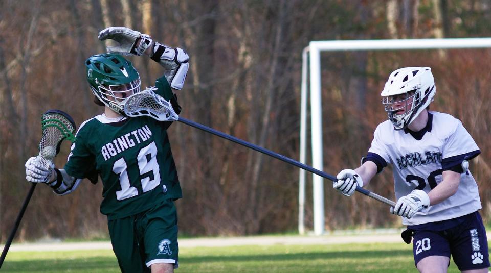 Patrick Prewitt of Abington gets a stick in the face from a Rockland defender during the lacrosse game in Rockland on Tuesday, April 4, 2023.