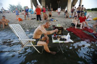 <p>A man sitting on a beach chair in his swimming trunks takes his meal at a small table partially dipped into the Hanjiang river to escape the summer heat, as other swimmers look on under a bridge in Wuhan, Hubei province, China, July 28, 2013. The highest temperature in Wuhan reached 37 degrees Celsius (98.6 degrees Fahrenheit) on Sunday, local media reported. (China Daily/Reuters) </p>