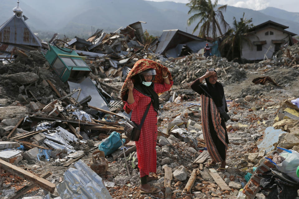 Indonesian women stand on the rubble as they look for what's left from a relative's house at Balaroa neighborhood in Palu, Central Sulawesi, Indonesia, Thursday, Oct. 11, 2018. Indonesia's search for victims buried in neighborhoods annihilated by an earthquake and tsunami is nearing its end almost two weeks after the double disasters hit the remote city. (AP Photo/Dita Alangkara)