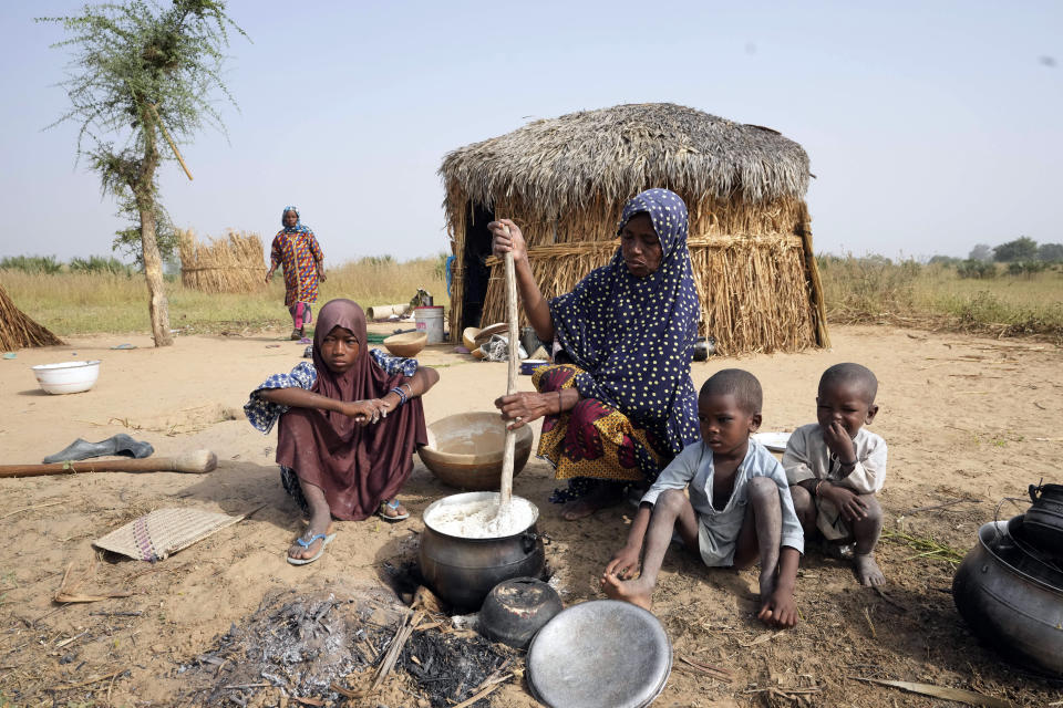 Aisha Ali, 40, sits with her children outside the hut where she found refuge from the floods in Darayami, northeastern Nigeria, Wednesday Oct. 26, 2022. When floodwaters reached her hut made of woven straw mats and raffia palms, she packed up what belongings she could and set off on foot with her eight youngest children. "While the flood was trying to destroy things, we were trying to save ourselves," she said. Four of her children perished. (AP Photo/Sunday Alamba)