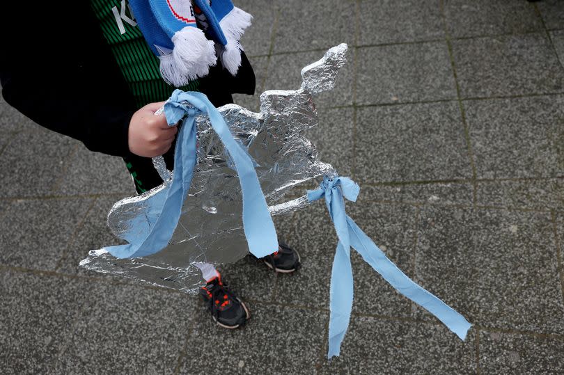 A fan with a cardboard FA Cup trophy