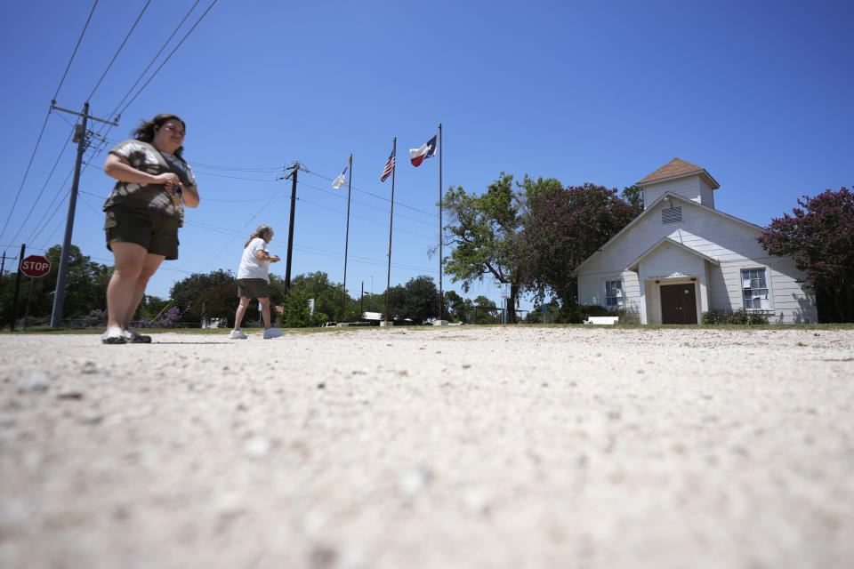 Onlookers visit the First Baptist Church in Sutherland Springs, Texas, Tuesday, July 2, 2024, which is now a memorial to the 26 people who were killed by a gunman in 2017. The 100-year-old building has served as a memorial since the shooting, but now some want to raze the building. (AP Photo/Eric Gay)