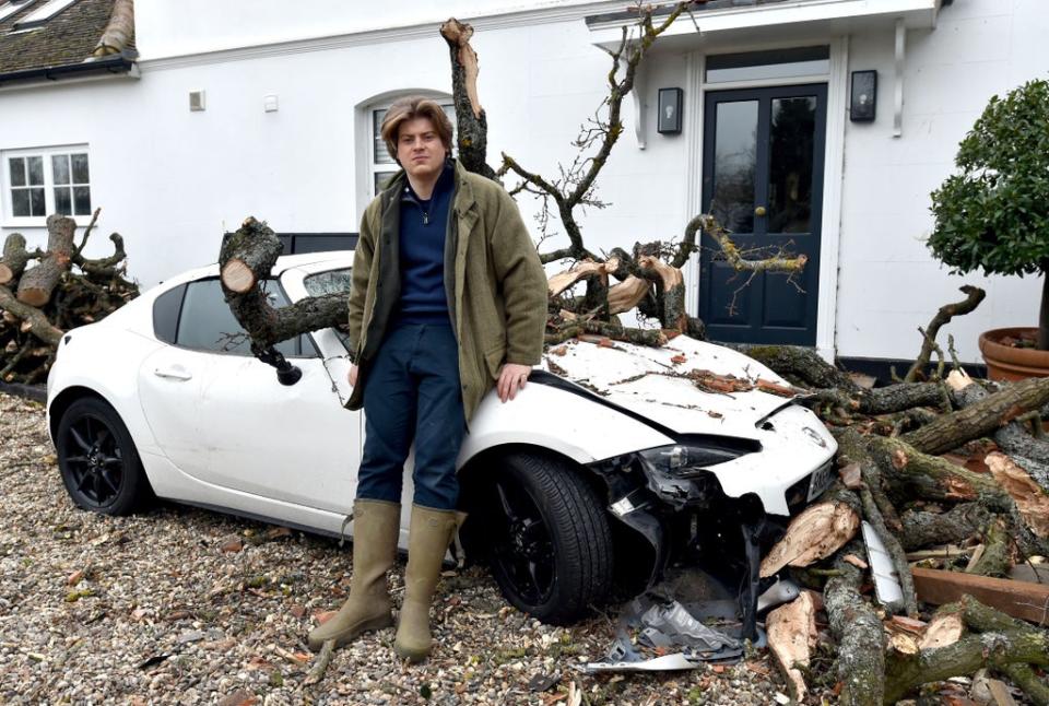 Sven Good, 23 sits on his tree damaged Mazda MX-5 outside the family home in Stondon Massey, near Brentwood (Nicholas T Ansell/PA) (PA Wire)