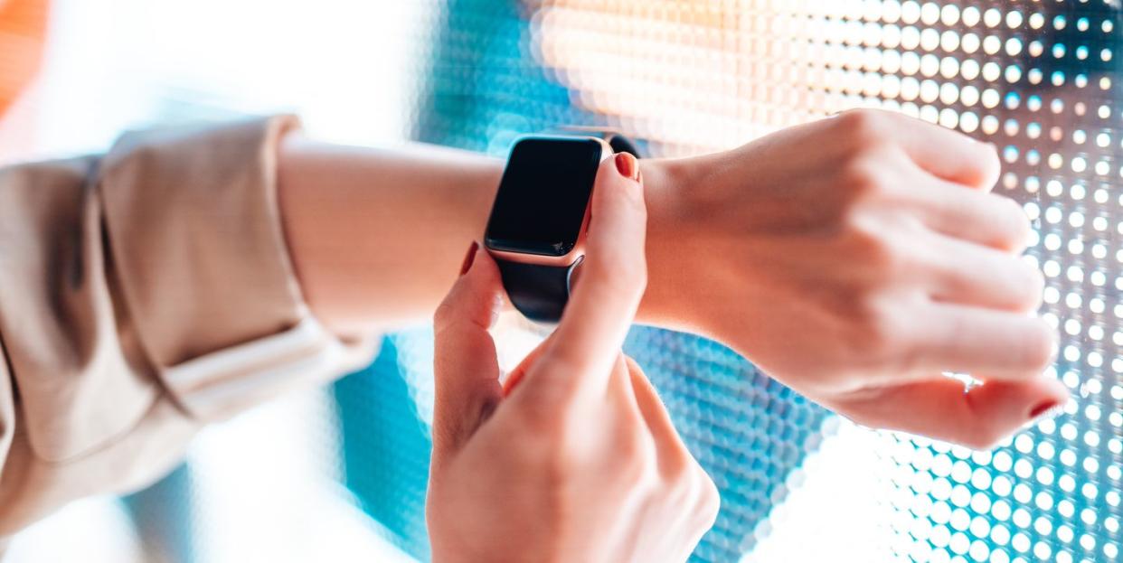 woman using smart watch against colourful neon light display