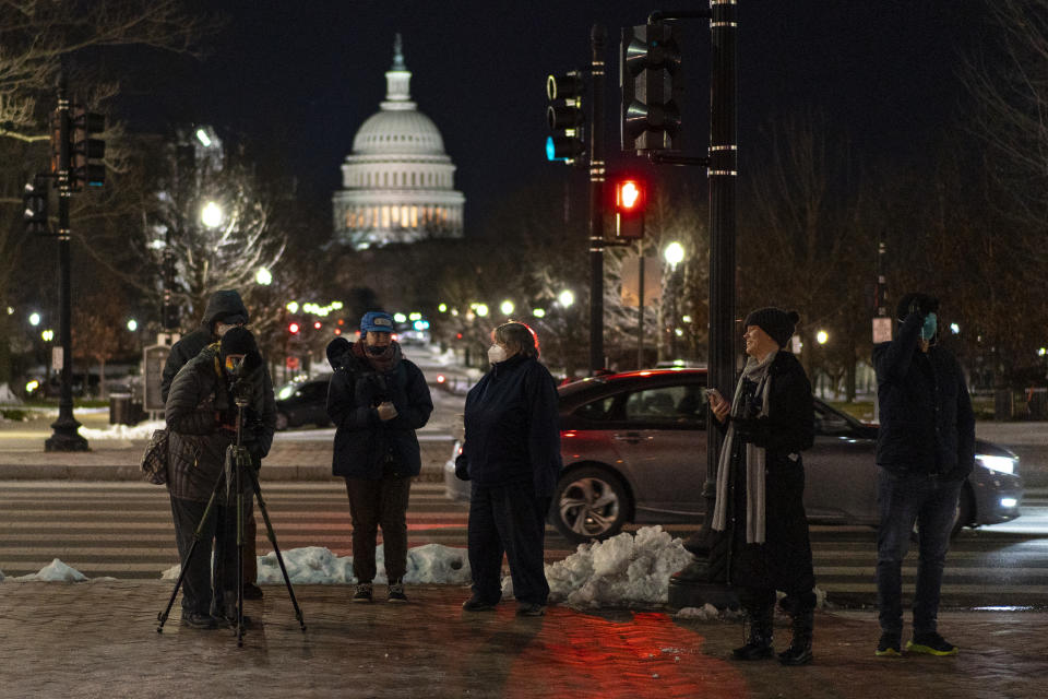 With the U.S. Capitol dome in the distance, birdwatchers line Columbus Circle in front of Union Station in Washington, Saturday, Jan. 8, 2022, hoping for a glimpse of a rare snowy owl that has been seen there and around Washington's Capitol Hill neighborhood. (AP Photo/Carolyn Kaster)