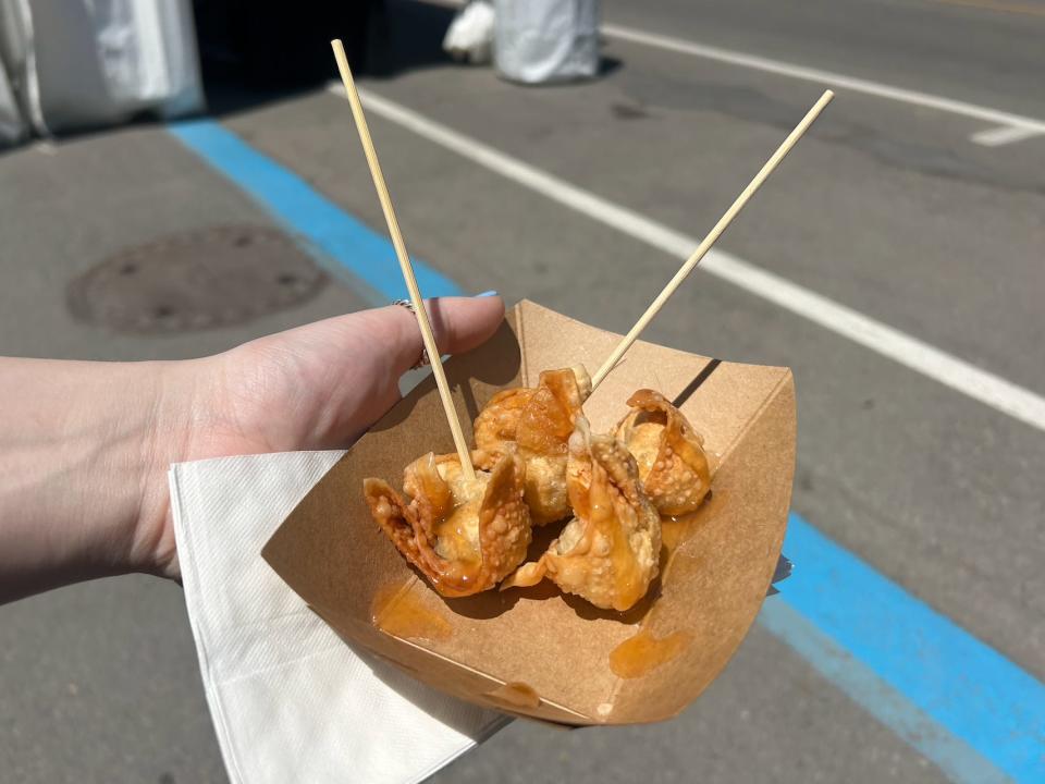 hand holding a container of fried wontons