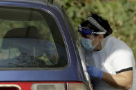 A person is tested for COVID-19 at a drive-through testing centre in a car park at Chessington World of Adventures, in Chessington, Greater London, Saturday, Sept. 19, 2020. England is preparing for more restrictions on gatherings and other activities in several areas of the country. There is growing speculation Britain may be sliding toward a lockdown in the coming weeks, partly because the testing regime is struggling to cope with higher demand. (AP Photo/Matt Dunham)