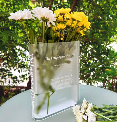 An acrylic book-themed flower vase