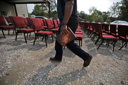 A local resident arrives for Sunday service as chairs are seen drying outside of Iglesia de Dios Pentecostal M.I. El Triunfo church in the first church service after Tropical Storm Harvey in east Houston, Texas. REUTERS/Carlos Barria