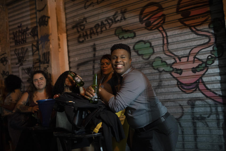 People listen to a street performance by the Brazilian band Atitude Nossa as the restrictions related to the COVID-19 pandemic are eased in Rio de Janeiro, Brazil, Monday, Oct. 5, 2020. Since the beginning of October, live shows are now permitted in Rio de Janeiro. (AP Photo/Silvia Izquierdo)