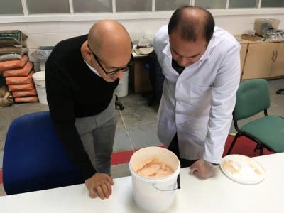 Lancaster University researchers Professor Mohamed Saafi and Hasan Hasan look into a bucket containing carrot mixture to be added to concrete, in their laboratory in Lancaster, Britain October 2, 2018. REUTERS/Jim Drury