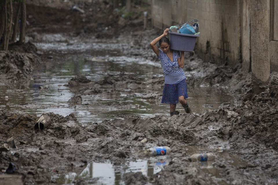 A resident continues to extract items from her home after it was flooded by last year's hurricanes Eta and Iota in the Saviñon Cruz neighborhood of San Pedro Sula, Honduras, Tuesday, Jan. 12, 2021. The devastation wrought by November's hurricanes and the economic damage of the COVID-19 pandemic has added to the forces of poverty and gang violence that drive Hondurans to migrate. (AP Photo/Moises Castillo)