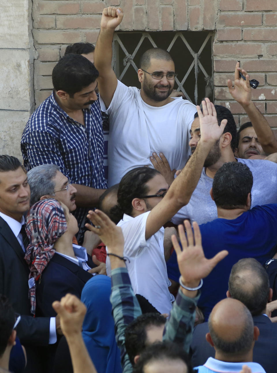 FILE - In this Aug. 28, 2014 file photo, surrounded by plainclothes policemen, Egyptian prominent blogger Alaa Abdel-Fattah waves to the crowd after attending the funeral of his father, Ahmed Seif, in Cairo, Egypt. A leading Egyptian pro-democracy activist was released from prison early Friday March 29, 2019, after serving a five-year sentence for inciting and taking part in protests, his family and lawyer said. (AP Photo/Hassan Ammar, File)
