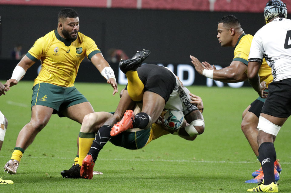 Australia's Tolu Latu, left, and Scott Sio right, watch as teammate David Pocock tackles a Fijian attacker during the Rugby World Cup Pool D game at Sapporo Dome between Australia and Fiji in Sapporo, Japan, Saturday, Sept. 21, 2019. (AP Photo/Aaron Favila)