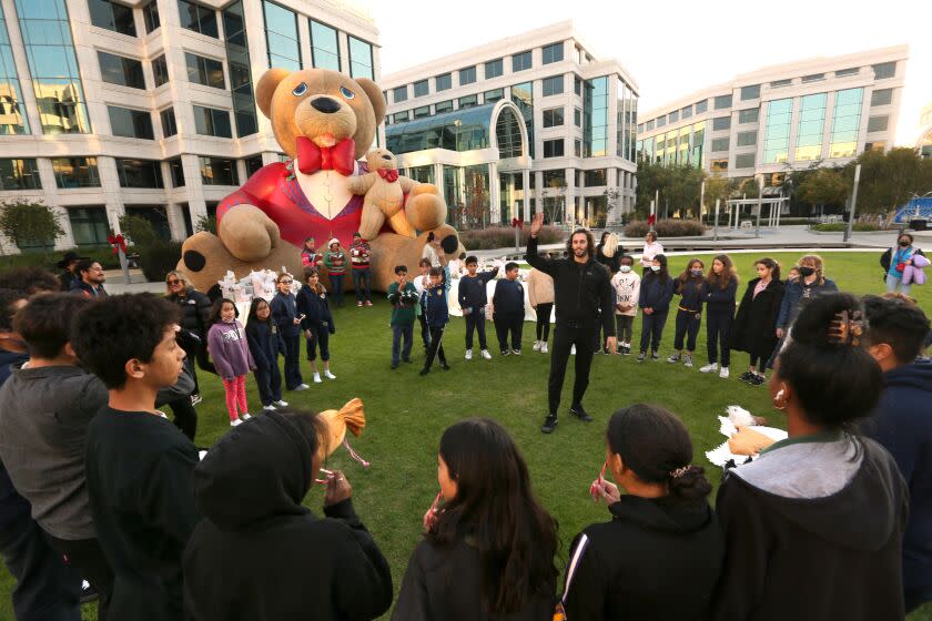 SANTA MONICA, CA - DECEMBER 13, 2022 - - Members of the Boys and Girls Club, with St. Anne School, take a dance class with dancer Tal Barnston, center, with Jacob Jonas The Company, in the courtyard at the Water Garden office complex in Santa Monica on December 13, 2022. Jacob Jonas The Company is one of the tenants at the Water Garden. CBRE brings in musical acts to entertain once a week, offers dance classes and a noon class on how to make floral arrangements as part of office landlords efforts to entice their tenants to stay. The pandemic has made successful programming harder because fewer people come to the office, but its importance has only grown as landlords try to make working in their buildings more appealing than working at home. (Genaro Molina / Los Angeles Times)