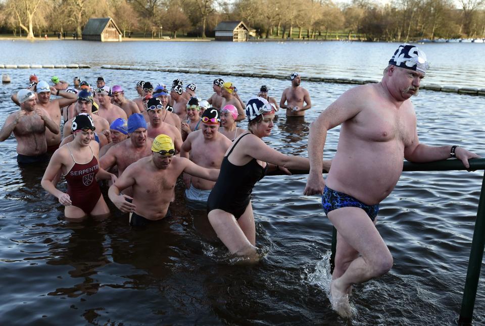 Competitors climb out of the water after taking part in the Peter Pan Cup open water swim in the Serpentine Lake at Hyde Park in London, December 25, 2014. Over one hundred swimmers took part in the annual Christmas Day event, swimming in water temperatures of 3-5 degrees celsius. REUTERS/Toby Melville (BRITAIN - Tags: SOCIETY ENVIRONMENT SPORT SWIMMING)