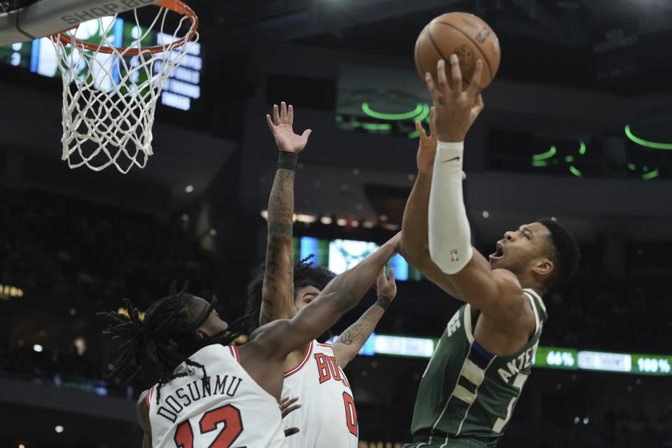 Milwaukee Bucks' Giannis Antetokounmpo shoots over Chicago Bulls' Ayo Dosunmu and Coby White during the first half of an NBA basketball game Monday, Dec. 11, 2023, in Milwaukee. (AP Photo/Morry Gash)